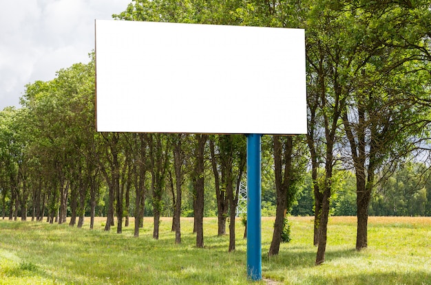 Maquette de panneau publicitaire blanc blanc debout dans le champ le long de la route