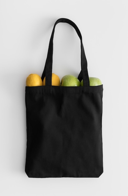 Maquette de sac fourre-tout noir avec des fruits sur un tableau blanc