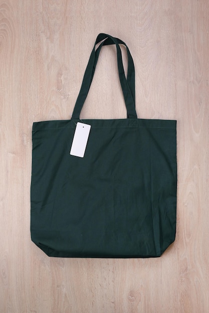 Photo maquette de sac en toile vert foncé avec étiquette sur fond en bois