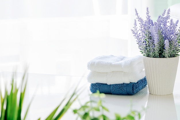 Maquette serviettes de bain sur une table blanche avec plante d'intérieur dans la salle blanche