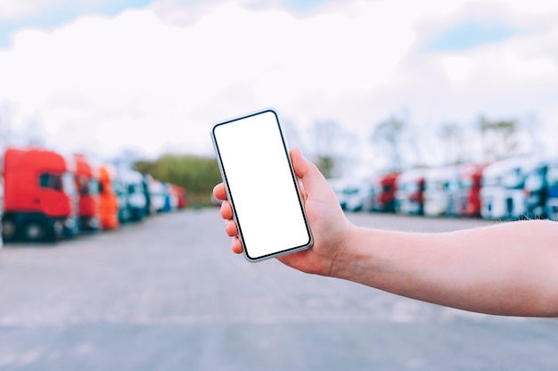 Photo maquette d'un smartphone dans la main d'un homme. dans le contexte des camions rouges. notion de logistique.