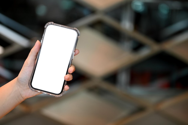 Une maquette de smartphone est dans la main de la femme sur une image agrandie d'arrière-plan flou