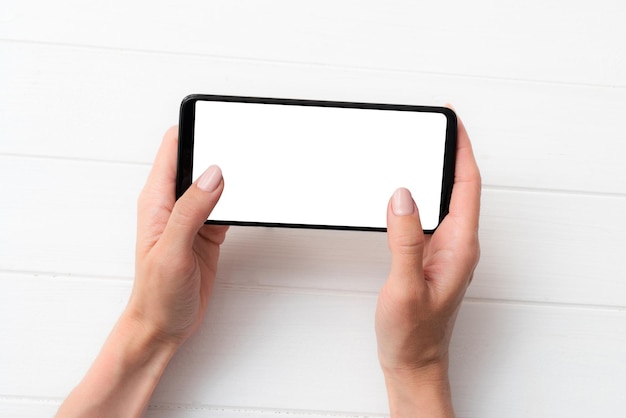 Maquette de smartphone noir dans les mains pour votre conception sur fond de tableau blanc