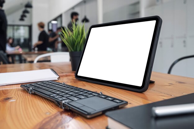 Maquette d'une tablette et d'un clavier portables à écran blanc vierge dans un espace de travail partagé.