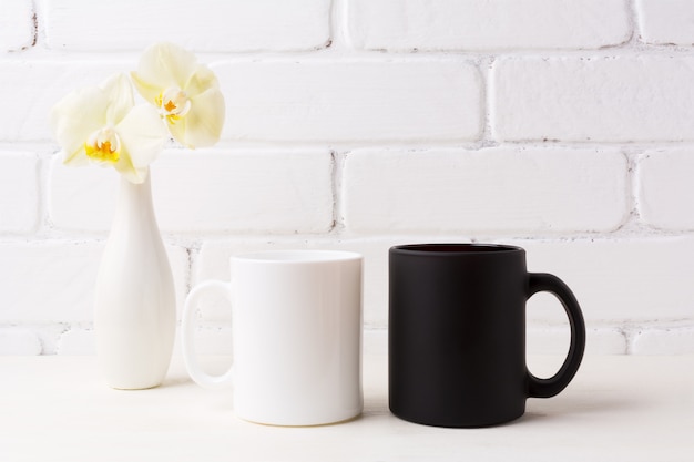 Photo maquette de tasse blanche et noire avec une orchidée jaune tendre dans un vase