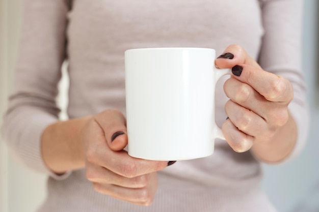 Maquette de tasse à café blanche pour la démonstration de conception tasse élégante maquette dans la main féminine