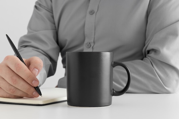 Maquette de tasse noire avec un homme prenant des notes