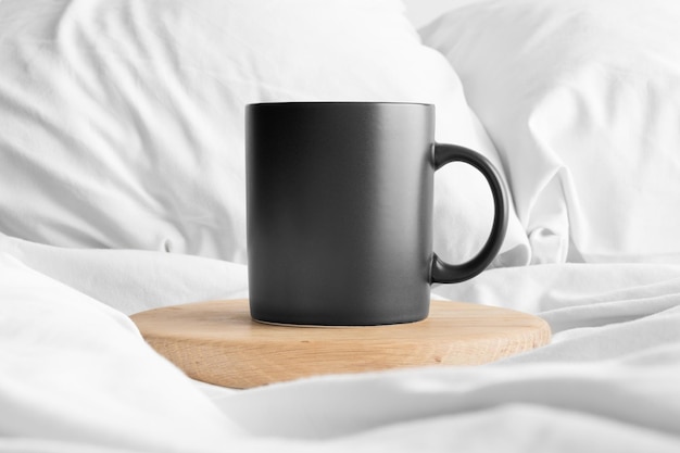 Maquette de tasse noire sur le lit