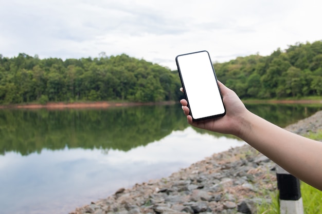 Maquette de téléphone portable sur le bord de la rivière avec fond de nature verdoyante. concept d&#39;entreprise