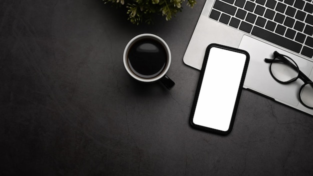 Maquette de téléphone portable avec une tasse à café d'ordinateur portable à écran blanc et des lunettes sur un tableau noir
