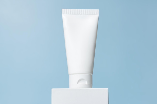 Maquette de tube cosmétique blanc Emballage en plastique pour produit crème de cosmétologie sur un podium blanc sur fond bleu Concept de soins de la peau