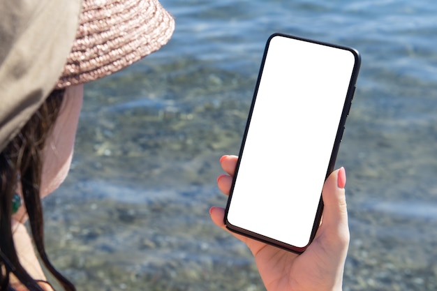 Maquette de vacances en mer de téléphone portable. Image de maquette d'une main tenant et montrant fond de mer de téléphone mobile blanc blanc