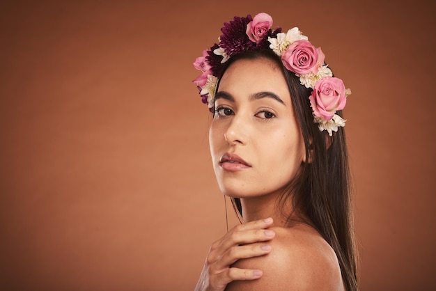 Maquillage beauté et femme avec couronne florale sur la tête pour modéliser les produits de beauté cosmétiques et la mode Cheveux créatifs et portrait artistique de fille avec bandeau de fleurs sur studio de fond marron