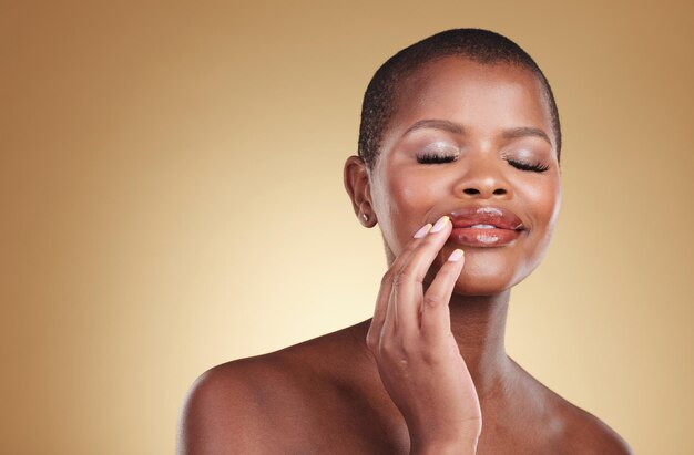 Photo maquillage beauté et une femme noire avec les mains sur la bouche en studio pour les soins de la peau et les cosmétiques visage d'une personne modèle africaine avec de la brillance sur les lèvres dermatologie et espace de maquette sur fond beige