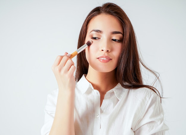 Maquillage Brosse Dans La Main De La Souriante Jeune Femme Asiatique Avec De Longs Cheveux Noirs Sur Blanc