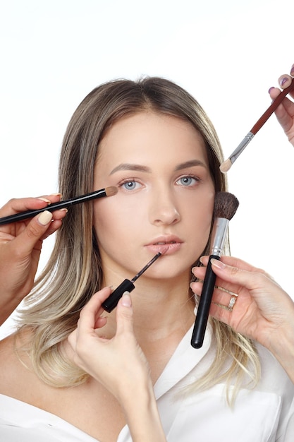 Maquillage femme avec de nombreuses mains pinceaux de maquillage ciseaux ombres