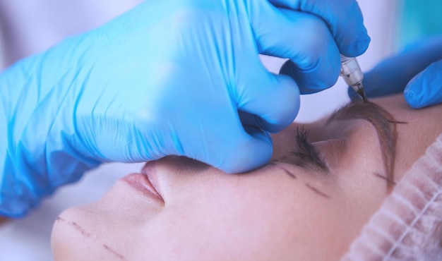 Maquillage permanent pour les sourcils Gros plan d'une belle femme aux sourcils épais dans un salon de beauté