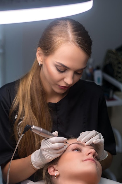 Maquillage permanent des sourcils Esthéticienne appliquant le tatouage des sourcils