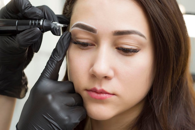 Maquillage permanent des sourcils. La fille dans le salon fait du maquillage permanent. Tatouage. Une fille dans un salon de beauté.