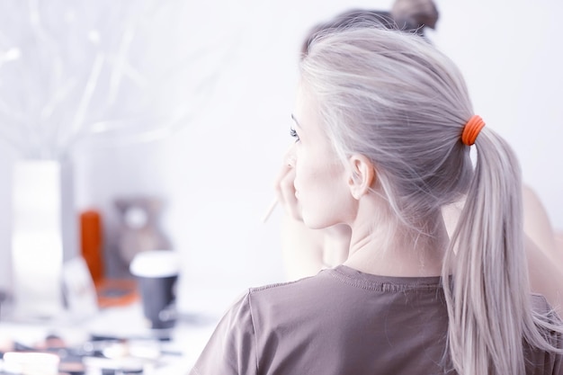 maquillage professionnel dans le salon de beauté / le maître fait un maquillage d'été frais et professionnel d'un beau modèle dans le salon