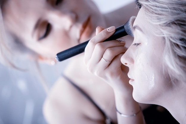 maquillage professionnel dans le salon de beauté / le maître fait un maquillage d'été frais et professionnel d'un beau modèle dans le salon