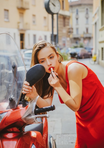 Maquillage de rue de mode dans la fille de mouvement a mis le rouge à lèvres regardant dans le miroir de la moto
