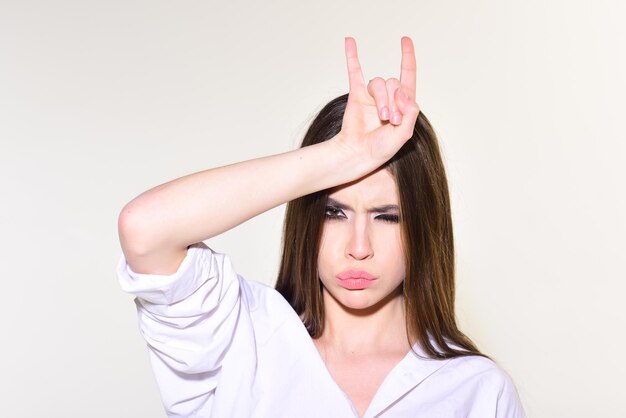 Maquillage yeux charbonneux pour modèle à la peau douce. Femme à la mode avec des cheveux élégants et un maquillage à la mode. Fille avec geste rock isolé sur blanc. Beauté et coiffeur. Concept de look de mode.