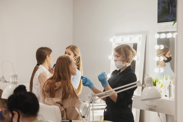 Les maquilleurs composent de jeunes femmes dans un salon de beauté