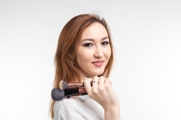 Maquilleuse, concept de beauté et de personnes - belle jeune femme coréenne tenant des pinceaux de maquillage sur