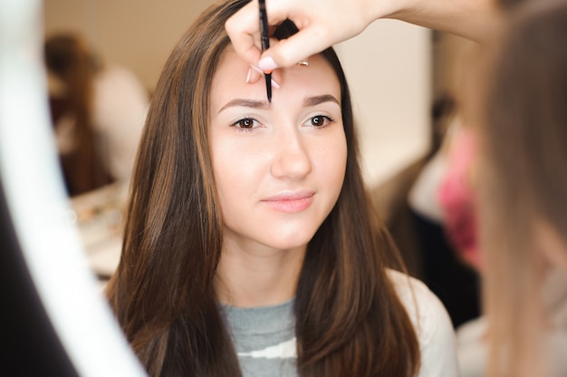 Maquilleuse faisant un maquillage professionnel de jeune femme.