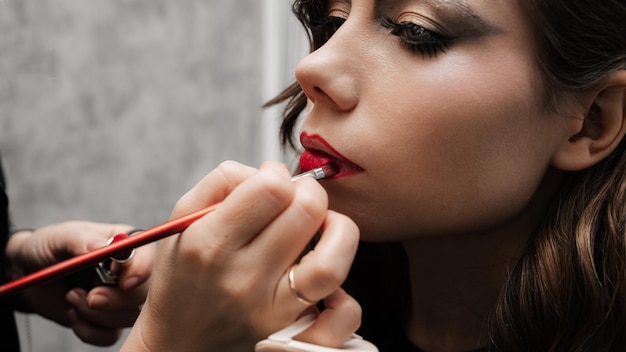 Une maquilleuse fait du maquillage pour les lèvres d'une jeune fille dans un salon de beauté