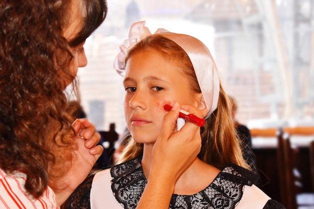 Maquilleuse maquille un mannequin de jeune fille.