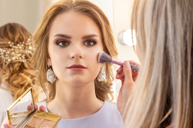 Maquilleuse met le maquillage sur le modèle de fille