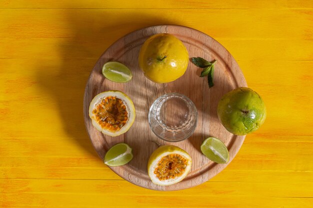 Maracuja, fruit de la passion sur table en bois en vue de dessus à plat avec demi-citron et verre vide. Fruit exotique