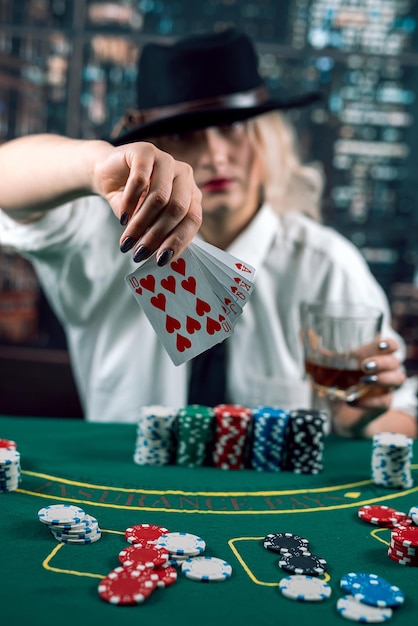 Une marchande ou un croupier mélange les cartes de poker dans le casino sur le fond de la table de jetons