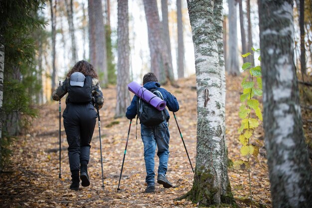 Marche nordique petit garçon et jeune femme vue arrière forêt de bouleaux