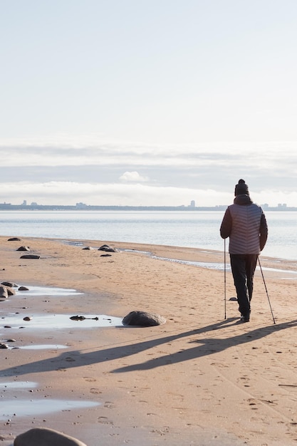 Marche nordique vue arrière sur des hommes européens caucasiens âgés marchant avec des cannes près du lac Exercices sportifs pour une thérapie saine de la colonne vertébrale et des articulations pour la santé vue de dos