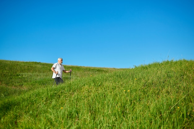 Marcher avec des bâtons de suivi sur l'air frais entre les collines herbeuses.