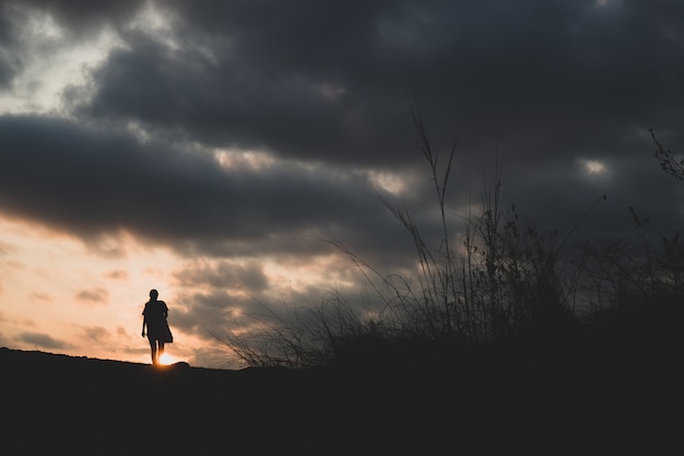 Marcher seul sur une colline avec coucher de soleil en arrière-plan