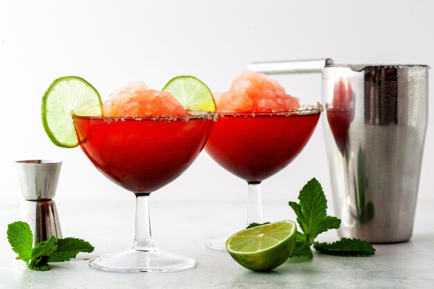 Margarita congelée rouge, cocktail rafraîchissant sur la table et citron vert à la menthe