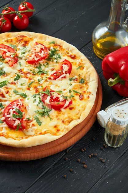 Margherita pizza au four avec tomates, fromage mozzarella et sauce rouge sur une surface en bois dans une composition avec des ingrédients