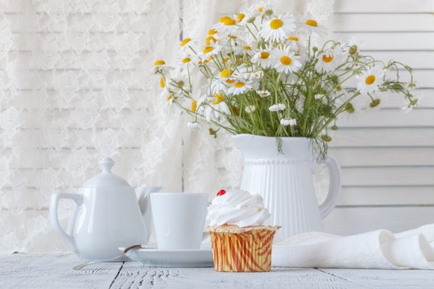 Marguerites fraîches Oxeye sur table en pichet blanc à l'intérieur