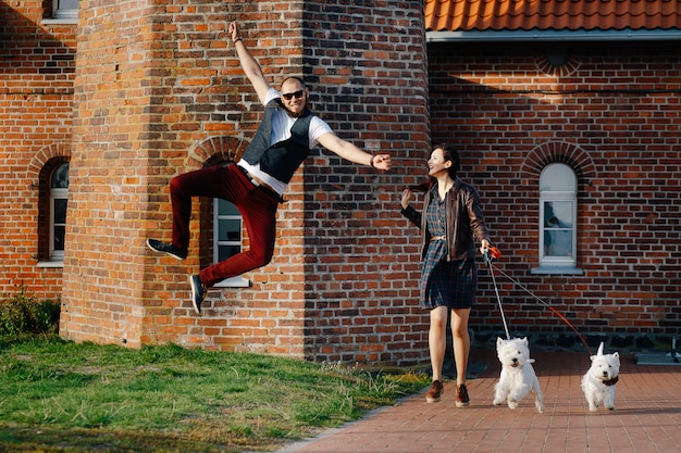 Photo mari avec une belle femme promenant leurs chiens blancs dans la rue