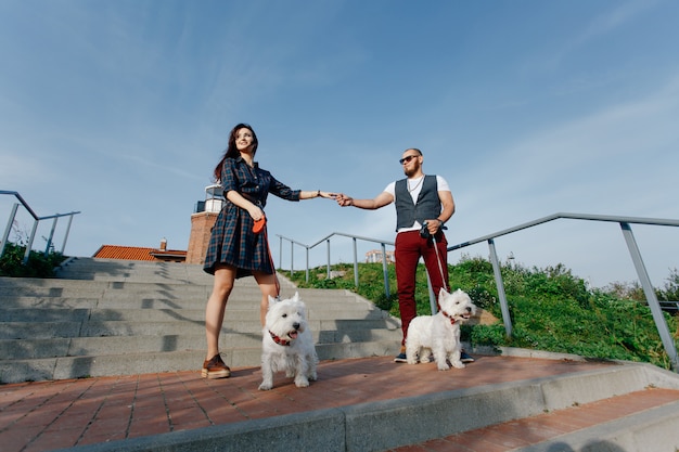 Photo mari avec une belle femme promener leurs chiens blancs dans la rue