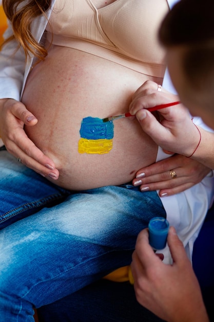 Le mari dessine le drapeau de l'Ukraine sur le ventre de sa femme