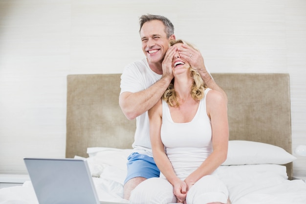 Mari faisant une surprise à sa femme dans son lit