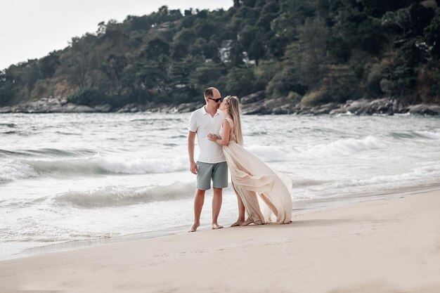 Mari et femme aimants vêtus de blanc s'embrassant sur une plage exotique; notion de relation.