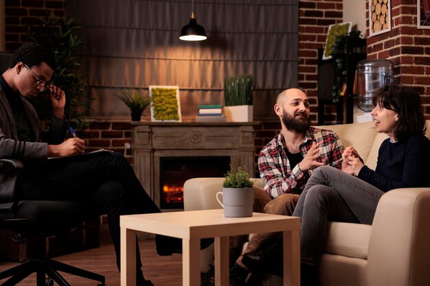 Mari et femme assistent à une séance de thérapie de couple avec un thérapeute masculin, essayant de résoudre des problèmes relationnels et se battant avec des conseils et de l'aide. Demander de l'aide pour des difficultés conjugales.