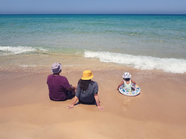 Mari femme et enfant sur une plage en Israël face à la mer Vue depuis l'arrière soft focus