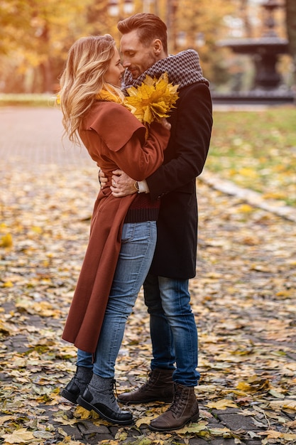 Photo mari et une femme étreint le sourire en se regardant dans le parc d'automne